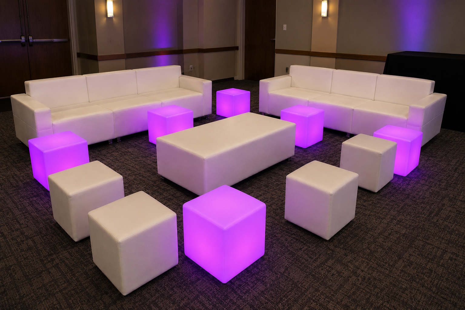 Two white modular sofas facing a bench ottoman surrounded by LED glow cubes