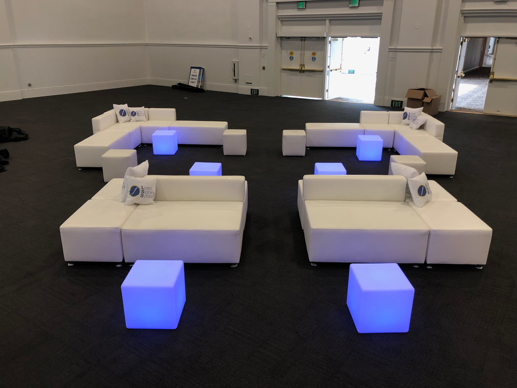 Four white modular lounge sets with blue LED cubes in a hotel ballroom