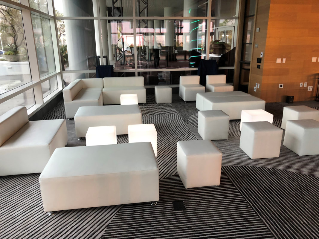 White modular sofas and ottoman cubes in a modern glass-walled lobby lounge
