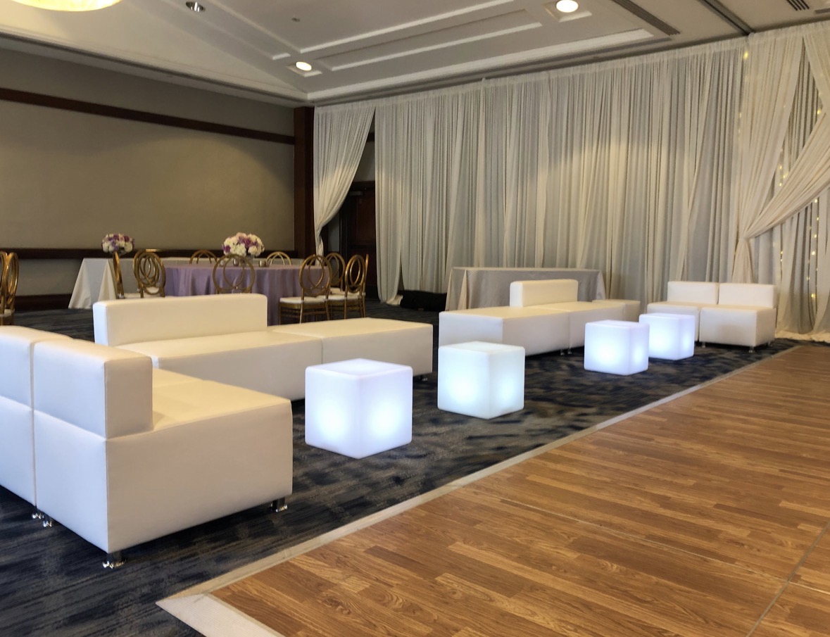 White modular lounge sofas and glowing LED cubes beside a ballroom dance floor